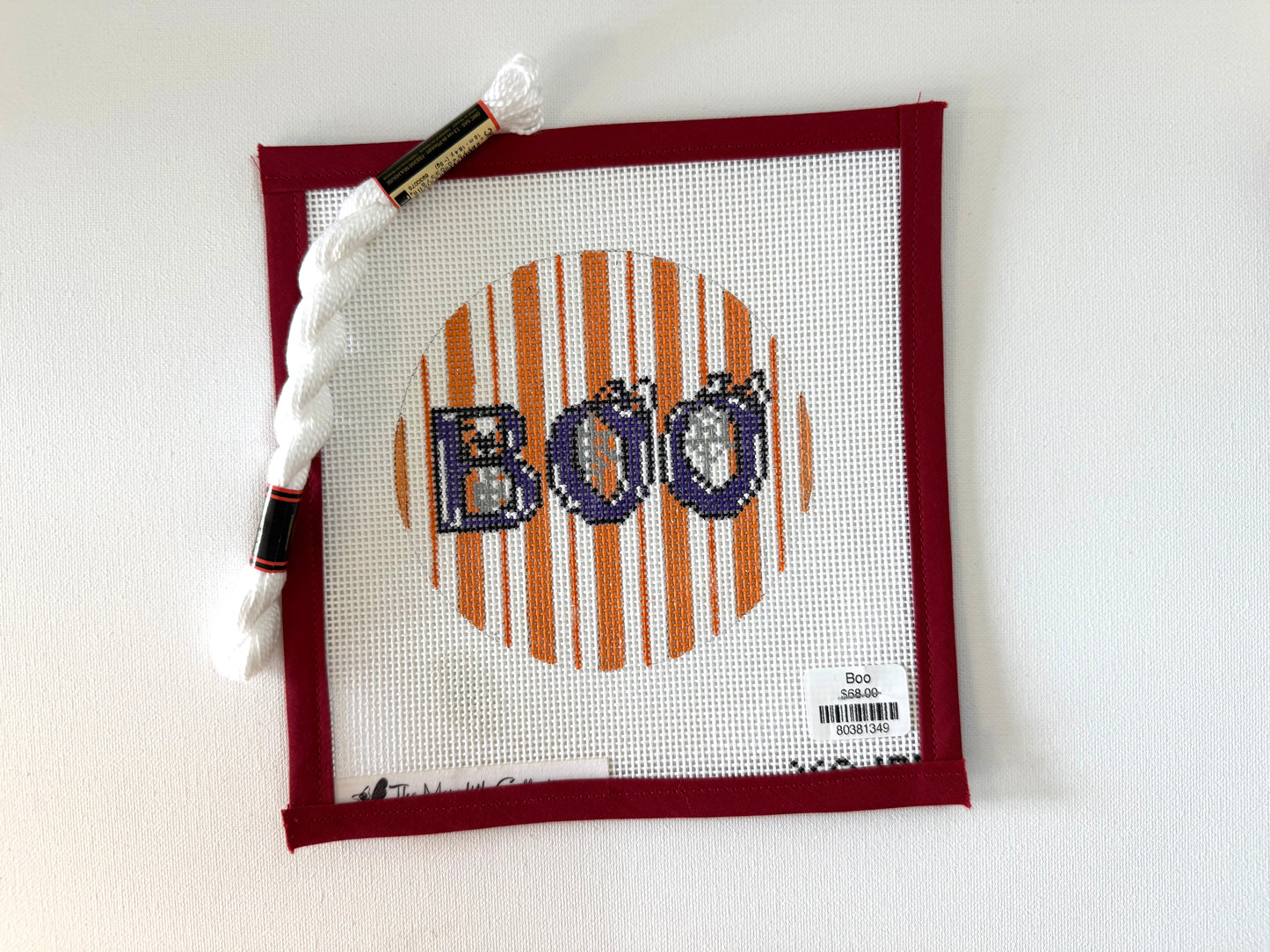 Cross-stitched hoop with 'Boo' design on white fabric, surrounded by a red frame.
