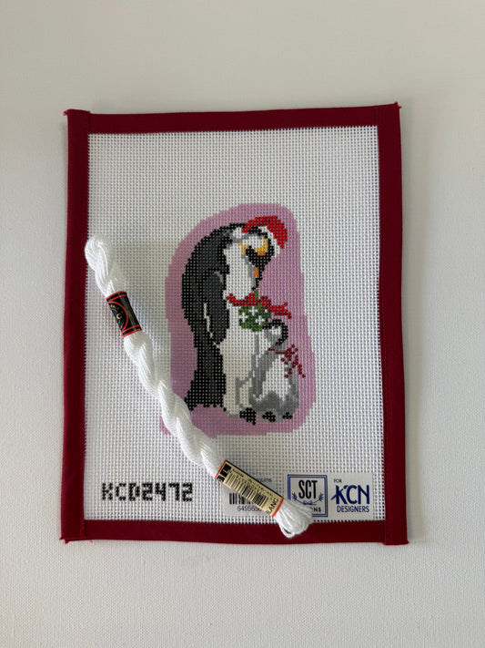 Cross-stitched penguin design on fabric with a needle and thread in the foreground.